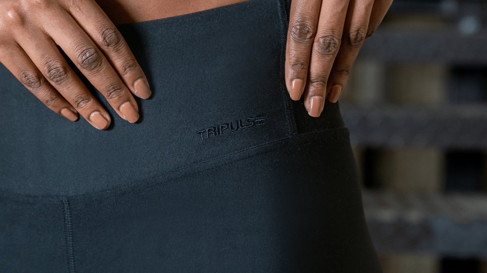 Close-up of hands resting on the waistband of dark TENCEL leggings.