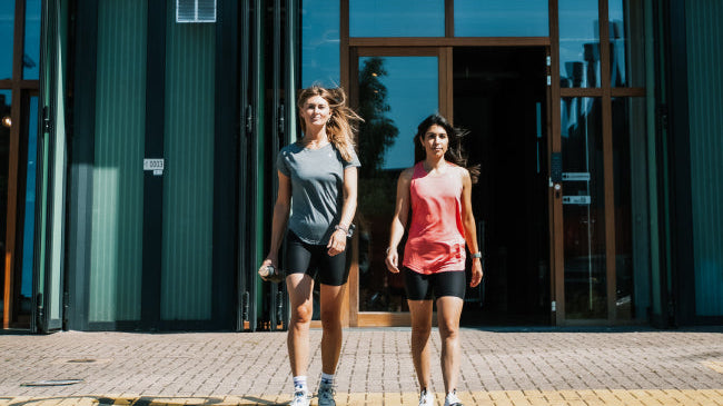 Two women walking out of the factory entrance in Tripulse activewear.
