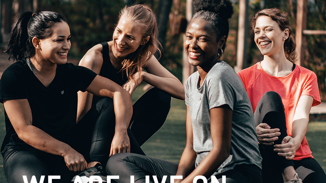 Four women laughing together outdoors in activewear with the caption We Are Live On Kickstarter.