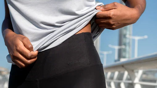 Woman lifting her white T-shirt to show the waistband of black TENCEL leggings.