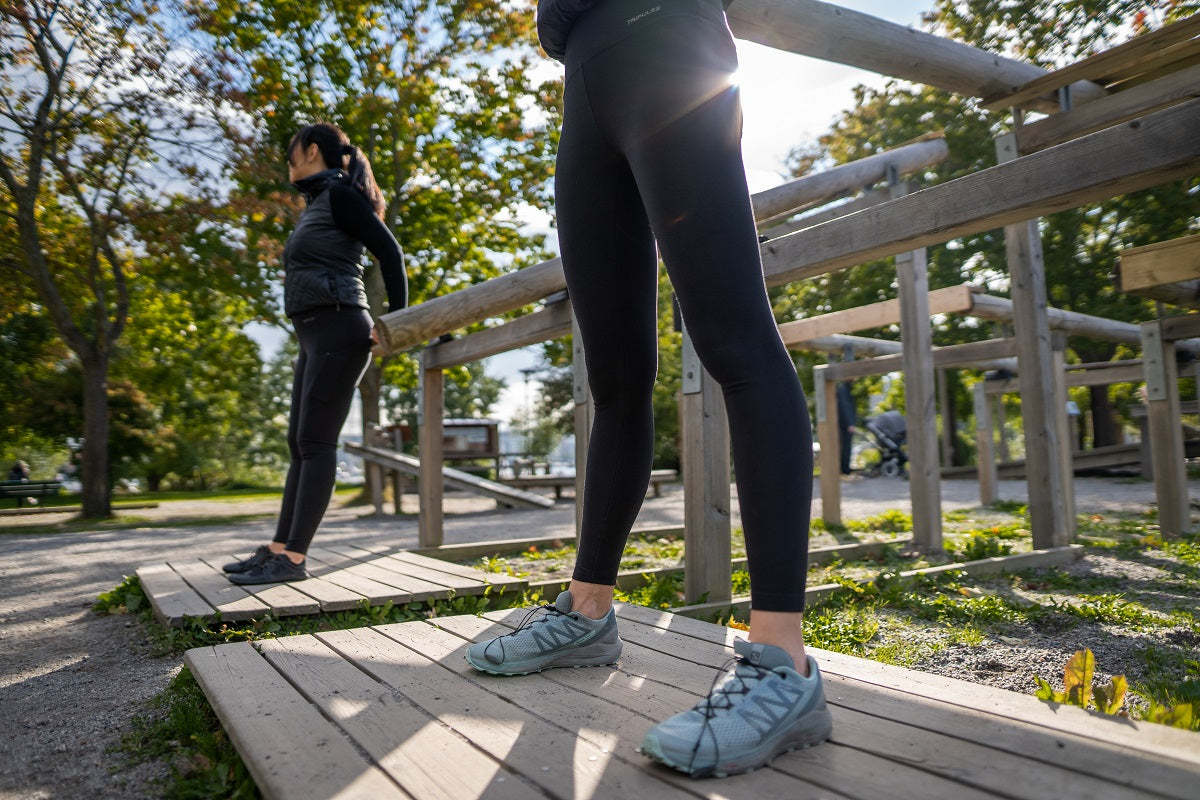 Close-up of legs in black TENCEL leggings climbing wooden outdoor steps.
