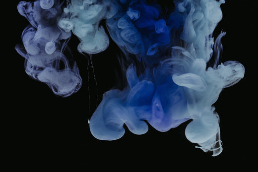 Blue and white ink clouds swirling in dark water.
