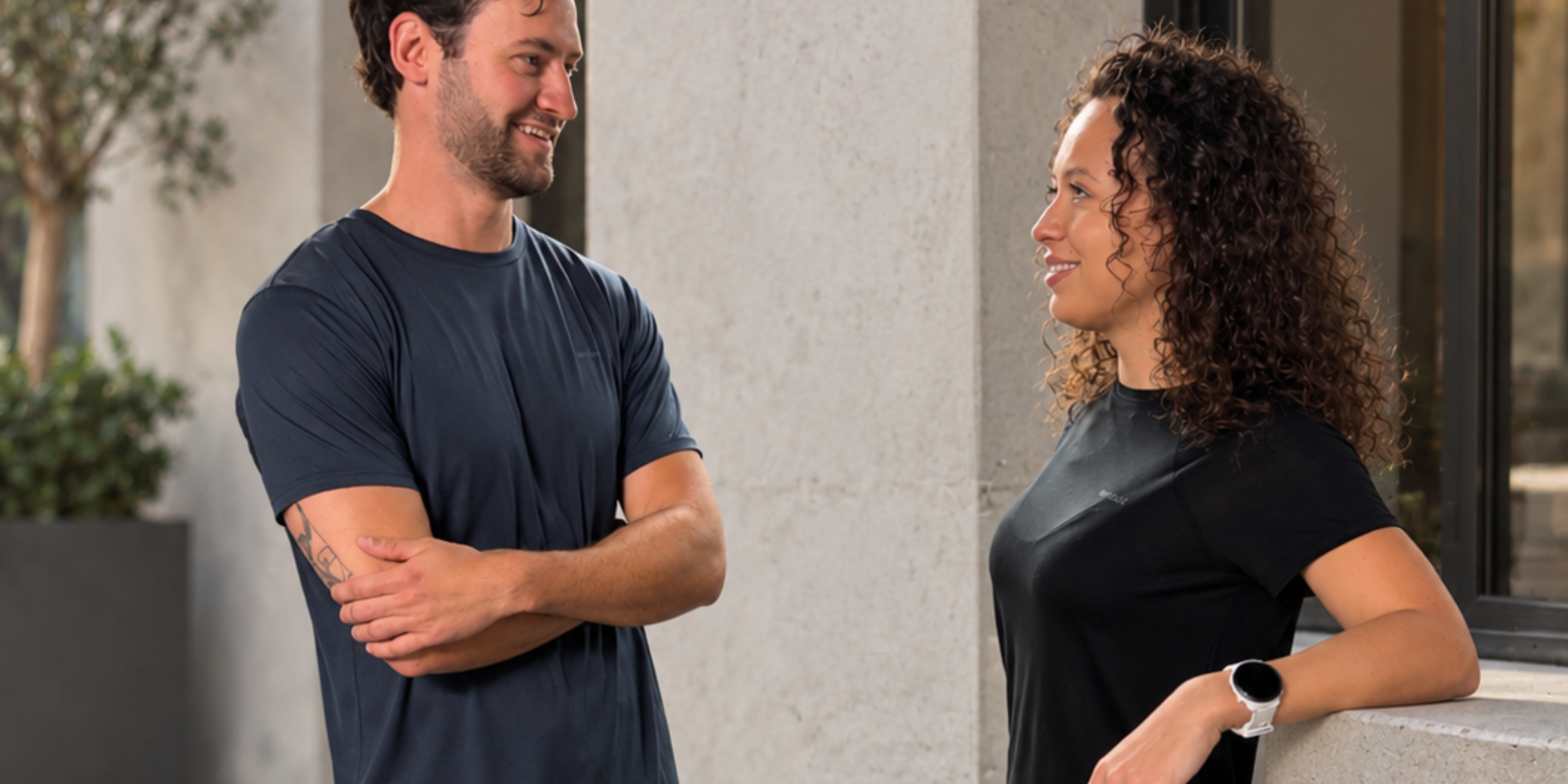 Man and woman in Tripulse t-shirts smiling at each other outdoors