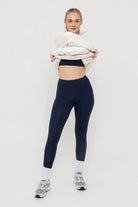 Woman wearing Tencel sports sports bra and leggings in midnight navy with cream sweatshirt
